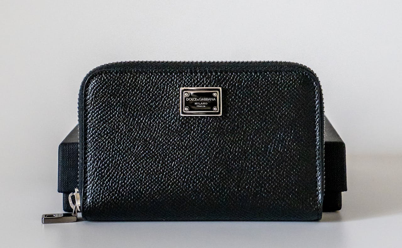 Elegant black leather wallet with metallic logo plate, ideal for fashion enthusiasts.
