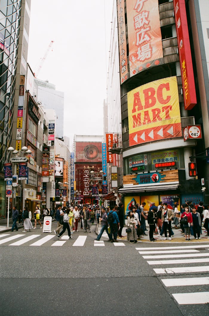 Vibrant crosswalk scene in Shibuya, Tokyo with pedestrians and colorful billboards.